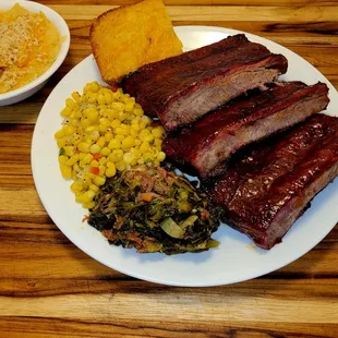 a plate of bbq meat, corn, and potatoes