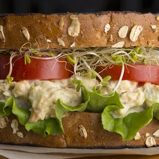 a sandwich with lettuce, tomato, and sprouts
