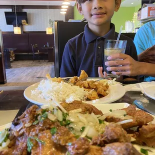 a boy sitting at a table with a plate of food and a glass of water