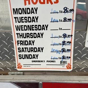 a business hours sign on the side of a building