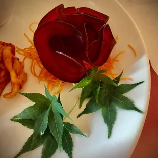 a white plate with a red rose on it