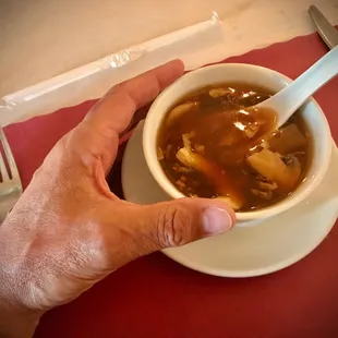 a person holding a spoon in a bowl of soup