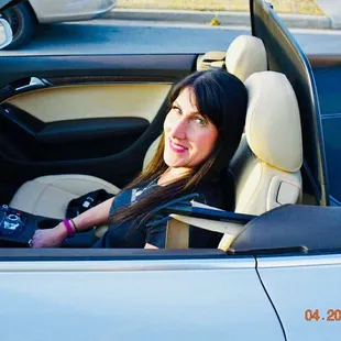 a woman sitting in the driver&apos;s seat of a convertible car