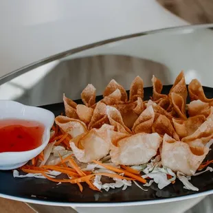 a plate of wontons with dipping sauce