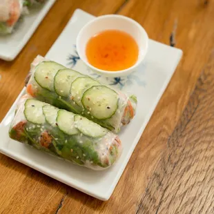 a plate of spring rolls and a bowl of dipping sauce