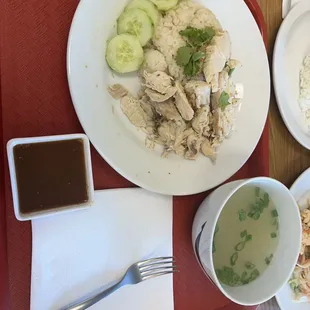 a plate of chicken, rice, cucumber, and sauce
