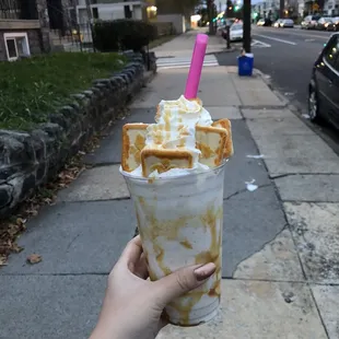 a hand holding a cup of ice cream