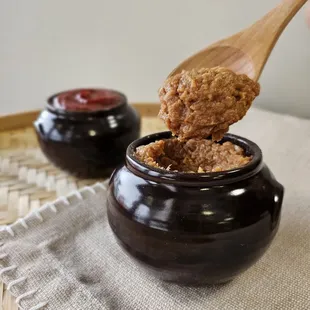 a person dipping a spoon into a jar of peanut butter