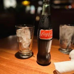 a bottle of coke and two glasses