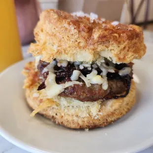 Sausage Biscuit which is a pork sausage patty with guava caramelized onions and shredded Kerry Gold cheddar cheese on a flavorful biscuit.