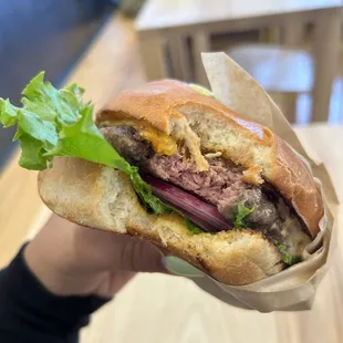 a hand holding a sandwich with meat and lettuce