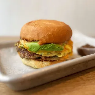 The Brekkie: Scrambled eggs, housemade pork sausage patty, cheddar, smashed taters, caramelized onions, jalapeño relish | $9.95 + $1.75 avo