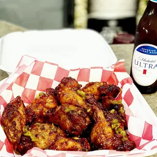 a basket of chicken wings and a bottle of beer