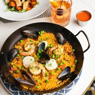 a plate of seafood and rice with a glass of orange juice