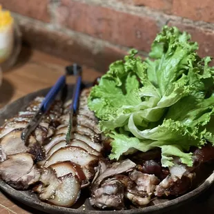 a plate of meat, lettuce, and chopsticks