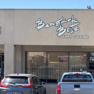 two cars parked in front of a thai restaurant