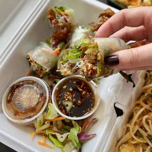 a hand picking up a piece of food from a styrofoam container