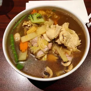 This a large bowl of Thai Chicken and Beef Noodle  Soup with vegetables.