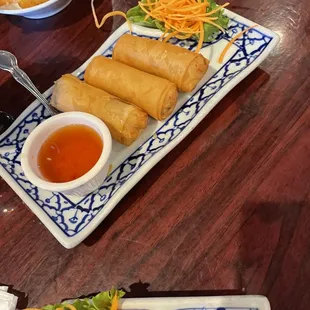 a plate of spring rolls and a bowl of dipping sauce