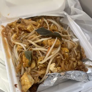 a take out container with noodles and tofu