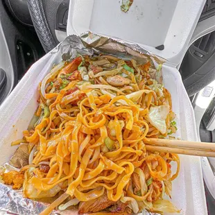 a take out container with noodles and chopsticks