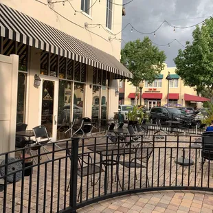 a sidewalk with tables and chairs
