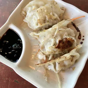 a plate of dumplings and a bowl of sauce