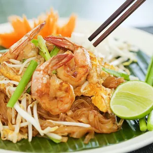 a plate of noodles with shrimp and vegetables