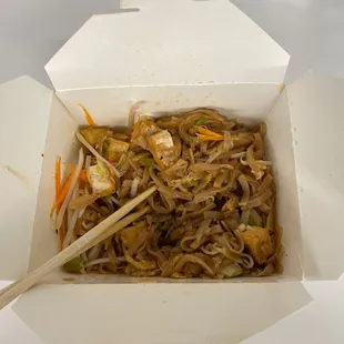a take out box of noodles with chopsticks