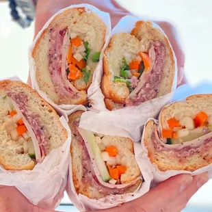 a person holding a bunch of sandwiches