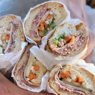 a person holding a bunch of sandwiches