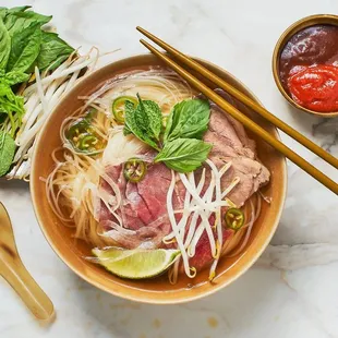 a bowl of vietnamese noodle soup with chopsticks