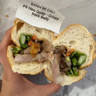 a hand holding a half eaten sandwich