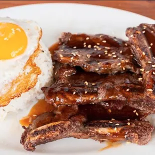 a plate of ribs, rice and an egg