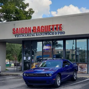 a blue car parked in front of a restaurant