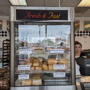 a woman standing in front of a fresh and fast bakery
