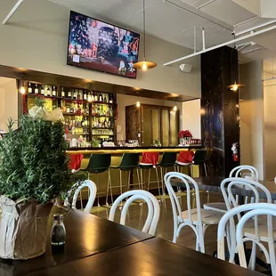 a bar with white chairs and a television