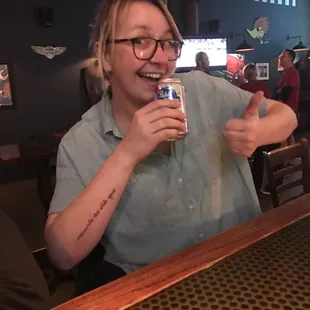 a woman sitting at a bar with a beer in her hand