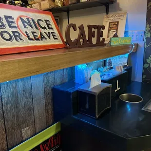 a coffee shop counter with a sign above it