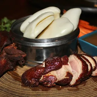 The Half Peking Duck is made with crispy duck, bao buns, vegetables, &amp; plum sauce.