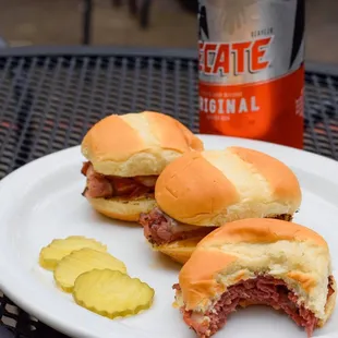 a plate with three sandwiches and a pickle