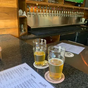 two glasses of beer and a menu