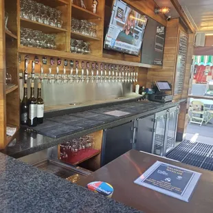 a bar with a television and wine glasses on the counter