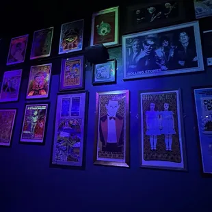 a wall full of posters and neon lights