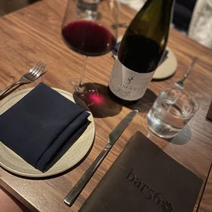 a table setting with a wine bottle, napkin, and wine glass