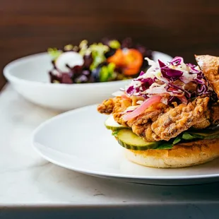 a chicken sandwich with a side salad