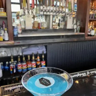 a blue drink in a martini glass