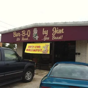ows two cars parked in front of a restaurant