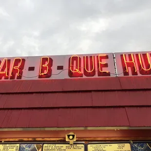 ows the neon sign for the bar - b - que hut