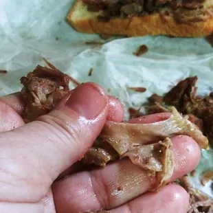 ows a hand holding a half eaten sandwich